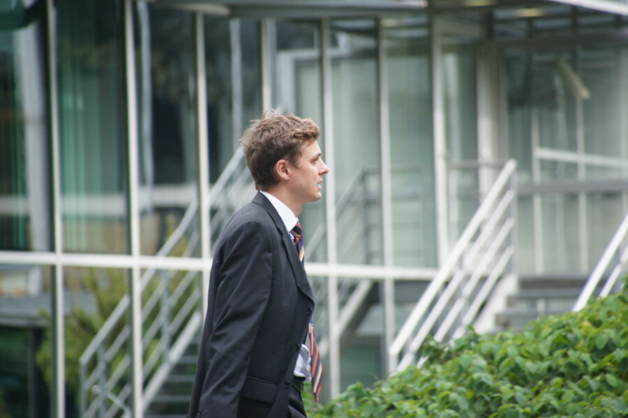 A business man is walking in front of an office building