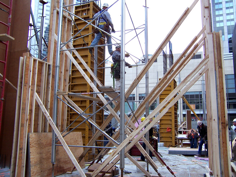 Workers assembling scaffolding to hold up the concrete forms of the second floor slab